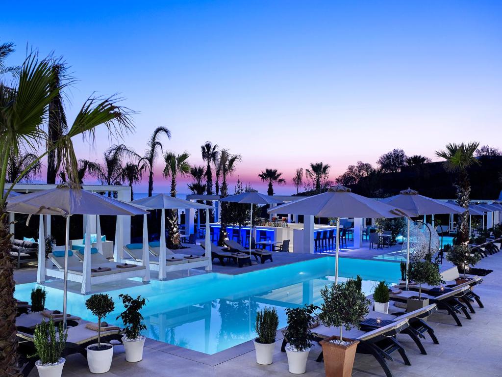 a pool with tables and umbrellas at a resort at Aurora Luxury Suites in Imerovigli