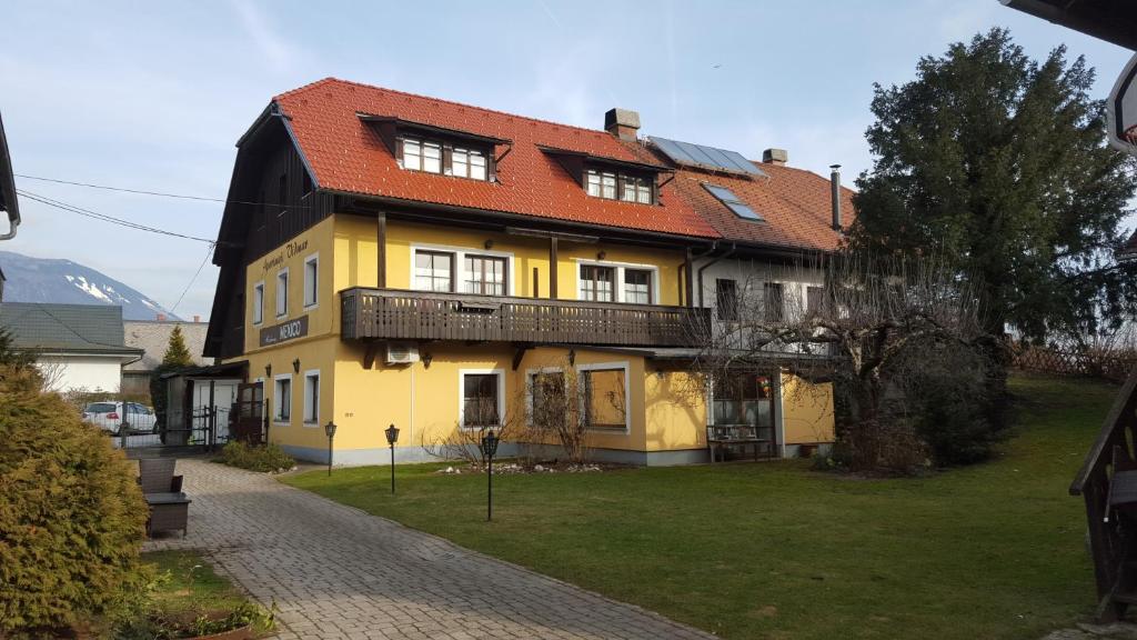 une maison jaune avec un toit rouge dans l'établissement Apartments Vidmar near Bled - Adults only, à Lesce