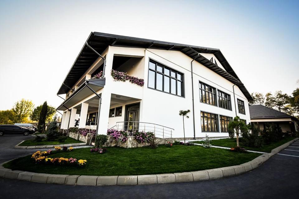 a large white building with flowers in front of it at Condor Resort in Dulceşti
