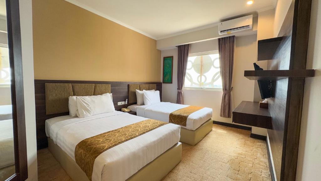 Postel nebo postele na pokoji v ubytování Lorin Syariah Solo Hotel