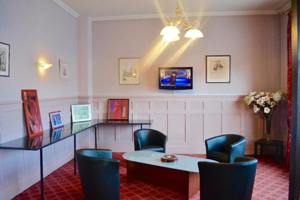 埃夫勒的住宿－格蘭德酒店，一间设有桌椅和电视的等候室