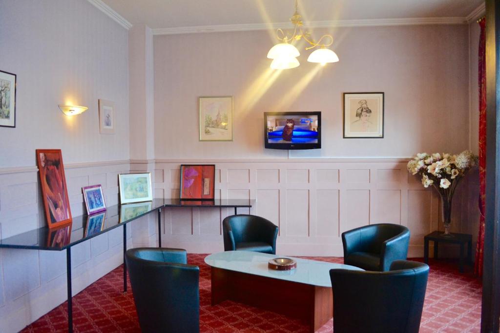 una sala de espera con mesa, sillas y TV en Grand Hotel De La Gare, en Évreux