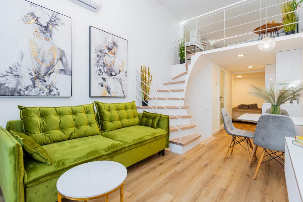 a living room with a green couch and a staircase at Palanga Suites in Palanga