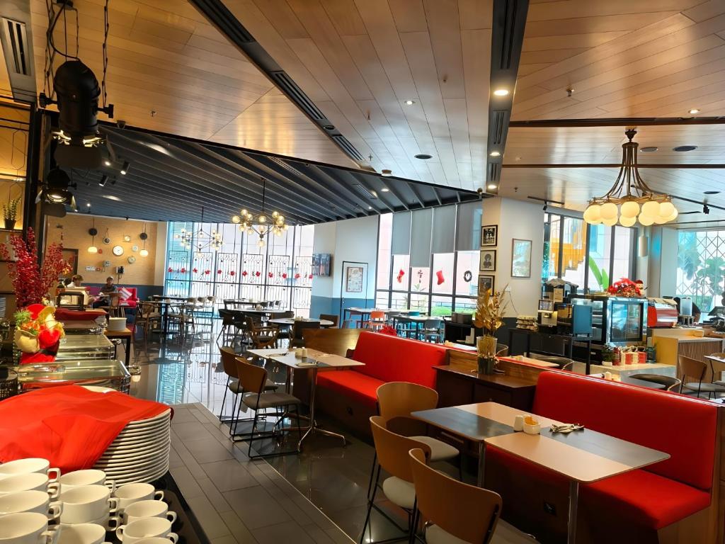 a restaurant with red chairs and tables and a cafeteria at The Kuala Lumpur Journal Hotel in Kuala Lumpur