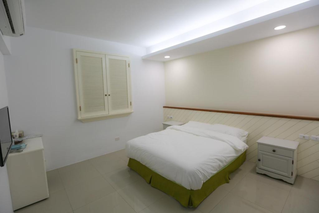 a white bedroom with a bed and a window at Return Home B&B in Yuli
