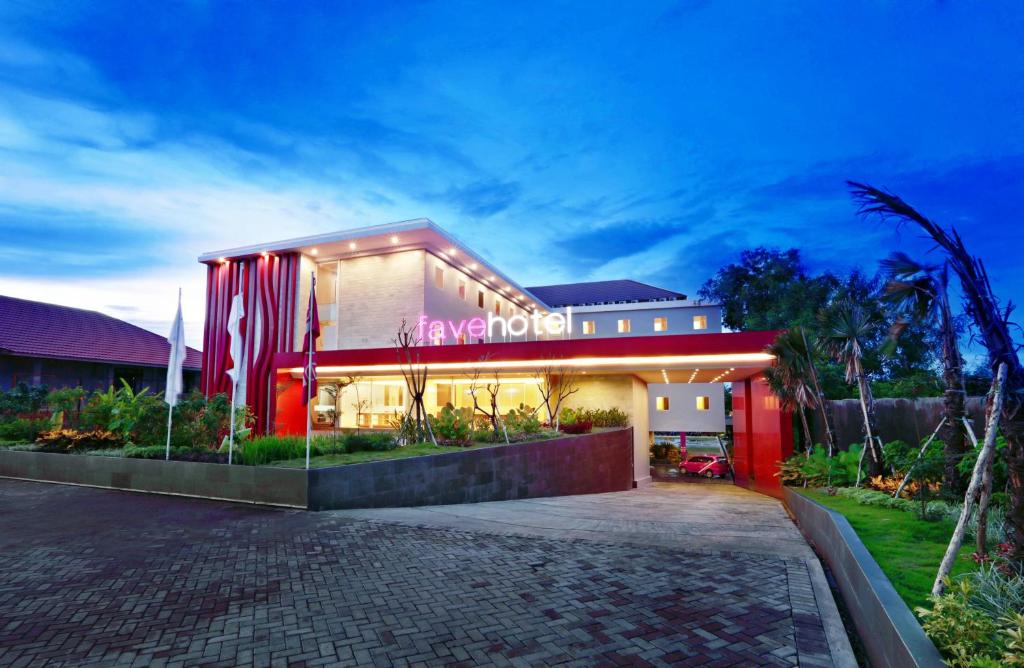 a building with a red facade with lights on at favehotel Banjarbaru in Banjarbaru