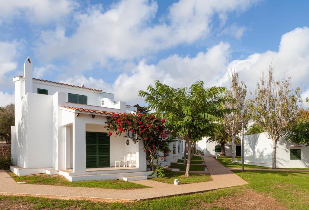 a white house with red flowers and trees at Minura Sur Menorca in Punta Prima
