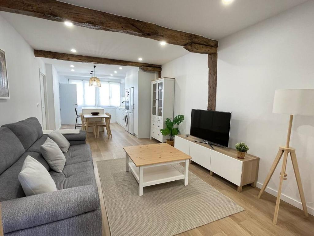 un soggiorno con un divano, una TV e un tavolo di Bidebarrieta Etxea , apartamento recién reformado a Bermeo