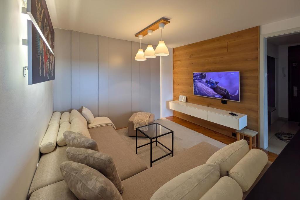 a living room with a large couch and a tv at Superbia Osijek - SELF CHECK-IN in Osijek