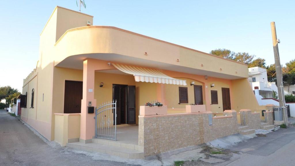 a small yellow house with a front porch at Villetta Giulia by Salento Affitti in Torre San Giovanni Ugento