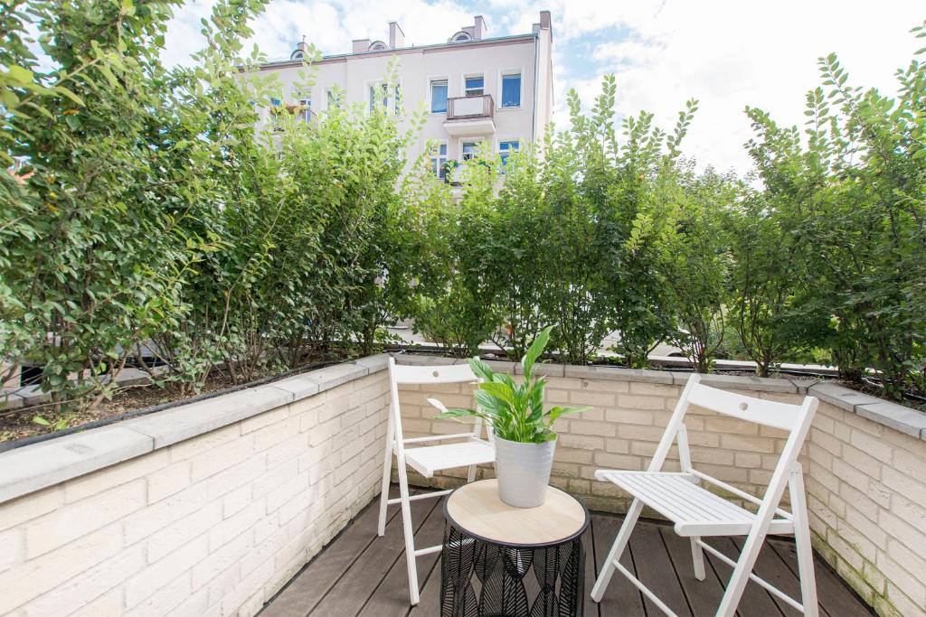 Small patio with two white folding chairs, round table and a potted plant.