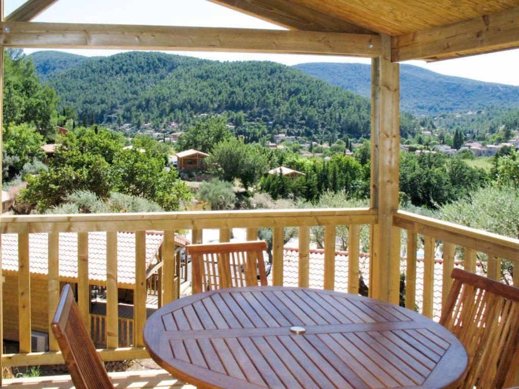 une table et des chaises en bois sur un porche avec vue dans l'établissement Cottage climatisé, piscine, nature, à Solliès-Toucas