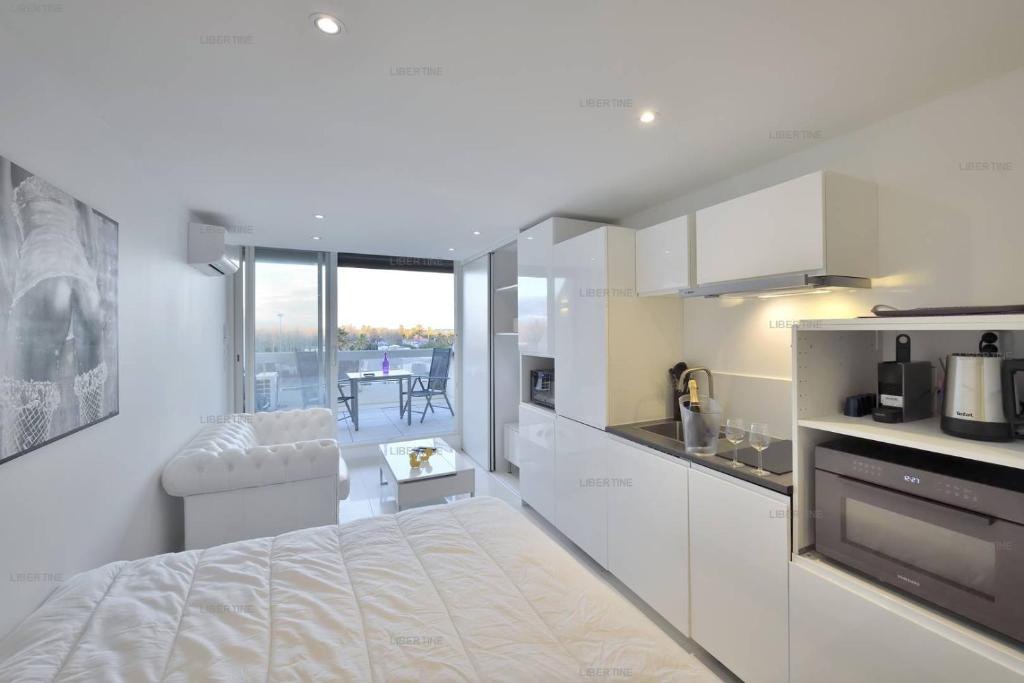 - une cuisine blanche avec un lit dans une chambre dans l'établissement Studio LIBERTINE - Héliopolis L 82 - Luxe - 2 personnes, au Cap d'Agde