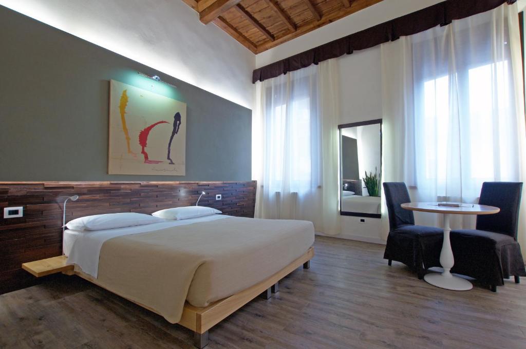 Alkimia Smart Rooms في فيرّارا: غرفة نوم بسرير وطاولة وكراسي