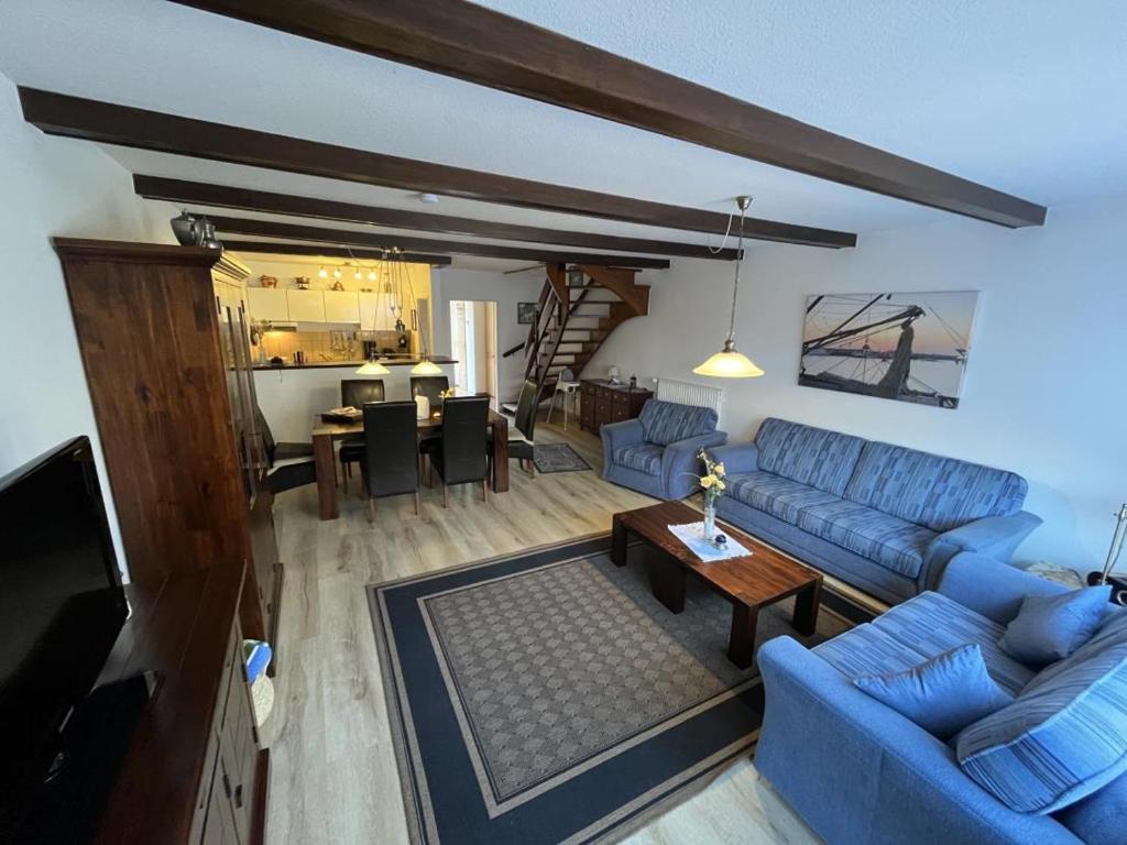 un salon avec un canapé bleu et une table dans l'établissement Ferienhaus Norddeich 27, à Norden