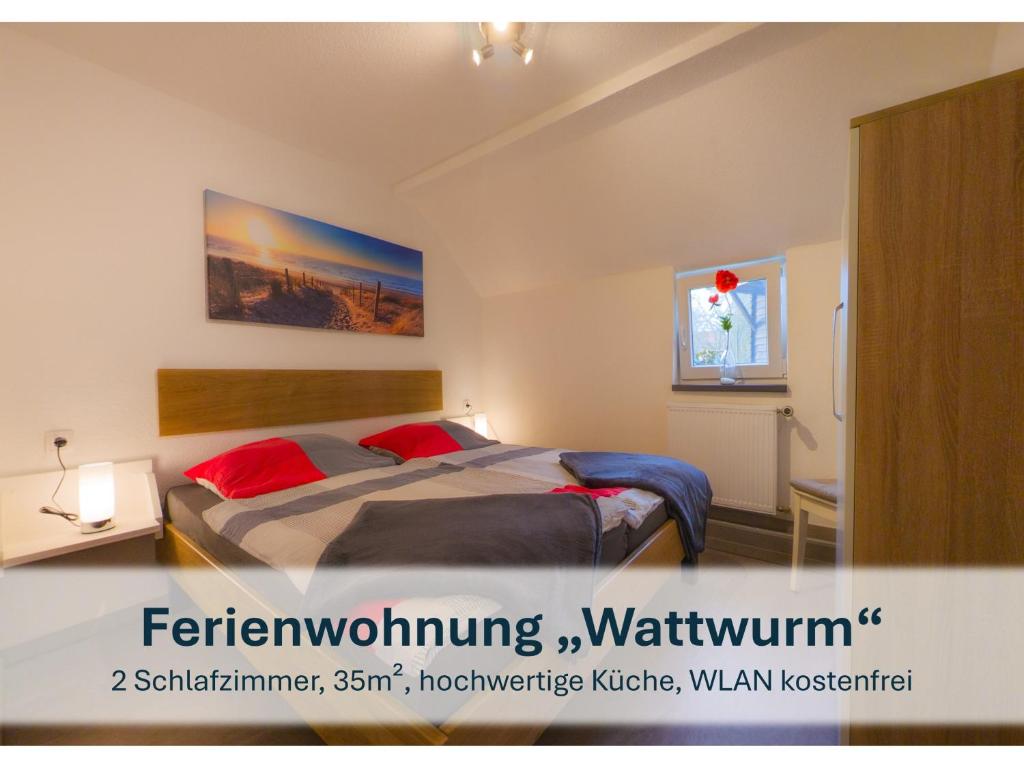 a bedroom with a large bed with red pillows at Stedesdorf, Ferienwohnung 'Nordsee-Wattwurm' in Stedesdorf