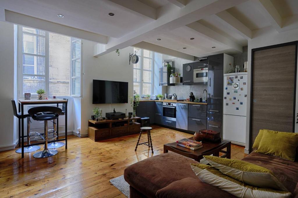 un salon avec un canapé et une cuisine dans l'établissement Jolie duplex au cœur de saint Michel, à Bordeaux
