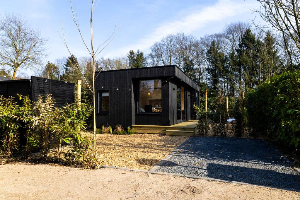 Ein schwarzes Haus mitten im Garten. in der Unterkunft Knus gezinsverblijf in Cosi Tiny House op de Veluwe in Epe