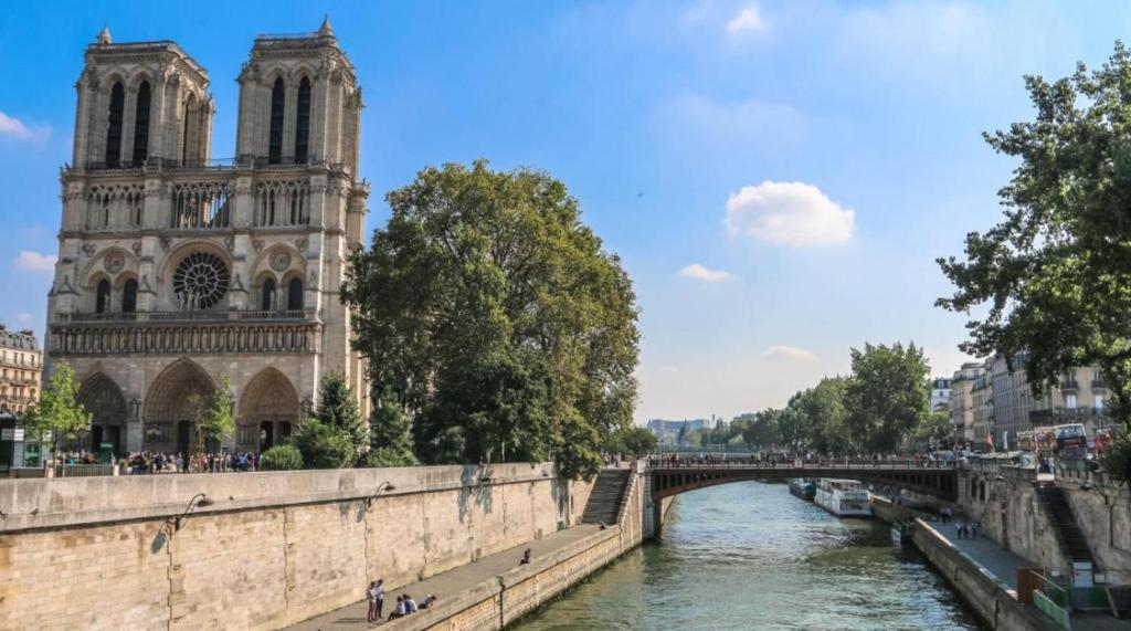 un pont sur une rivière en face d'une cathédrale dans l'établissement Sunny Paris studio in the heart of 11ème, à Paris