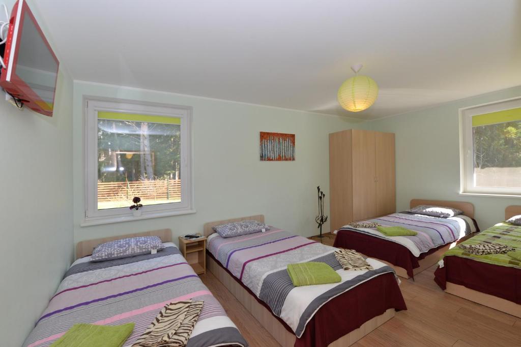 a room with three beds and a flat screen tv at Vanago Lizdas in Druskininkai