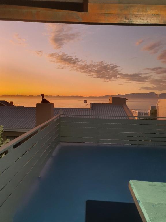 a swimming pool on the roof of a house with the sunset at KUSVAALBOS SELFSORG WOONSTEL in De Kelders