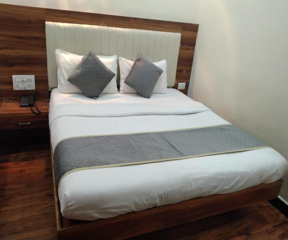 a bedroom with a bed with white sheets and pillows at HOTEL AIR VIEW Near Airport in Mumbai