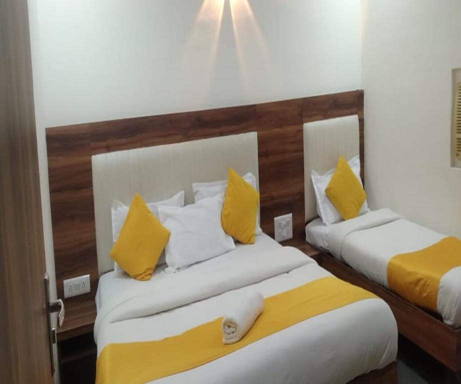 two beds in a room with yellow and white pillows at HOTEL AIR VIEW Near Airport in Mumbai
