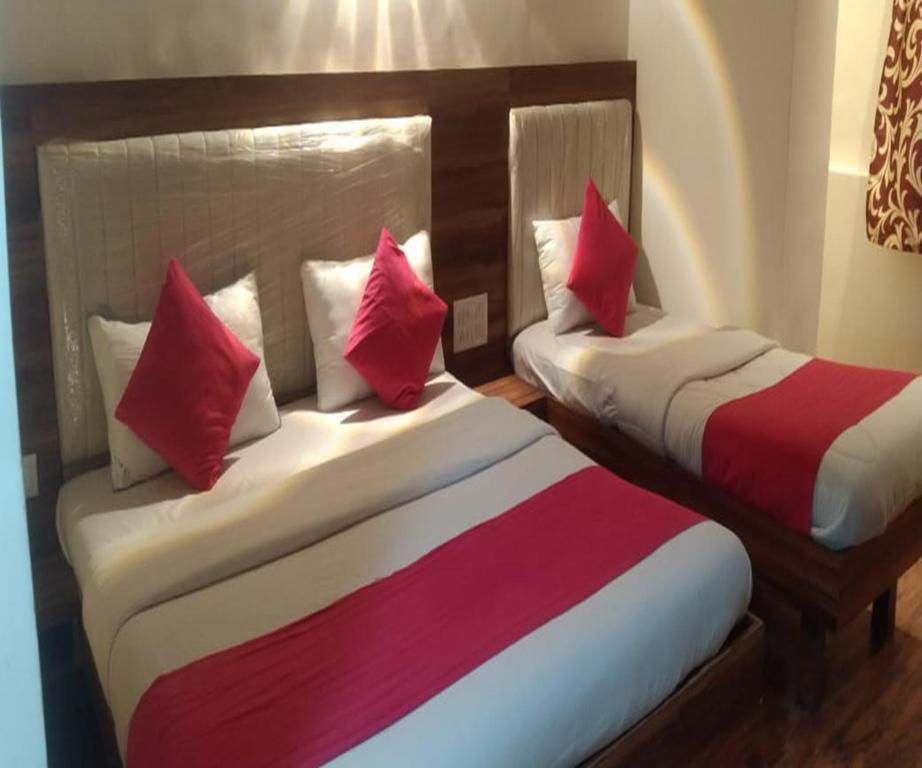 two beds in a hotel room with red and white pillows at HOTEL AIR VIEW Near Airport in Mumbai