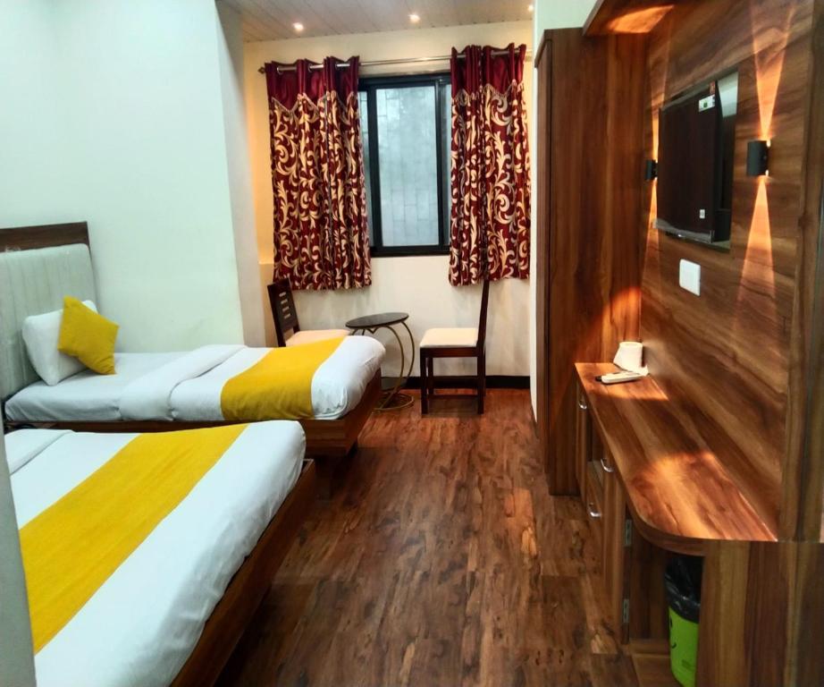 a hotel room with two beds and a desk at HOTEL AIR VIEW Near Airport in Mumbai