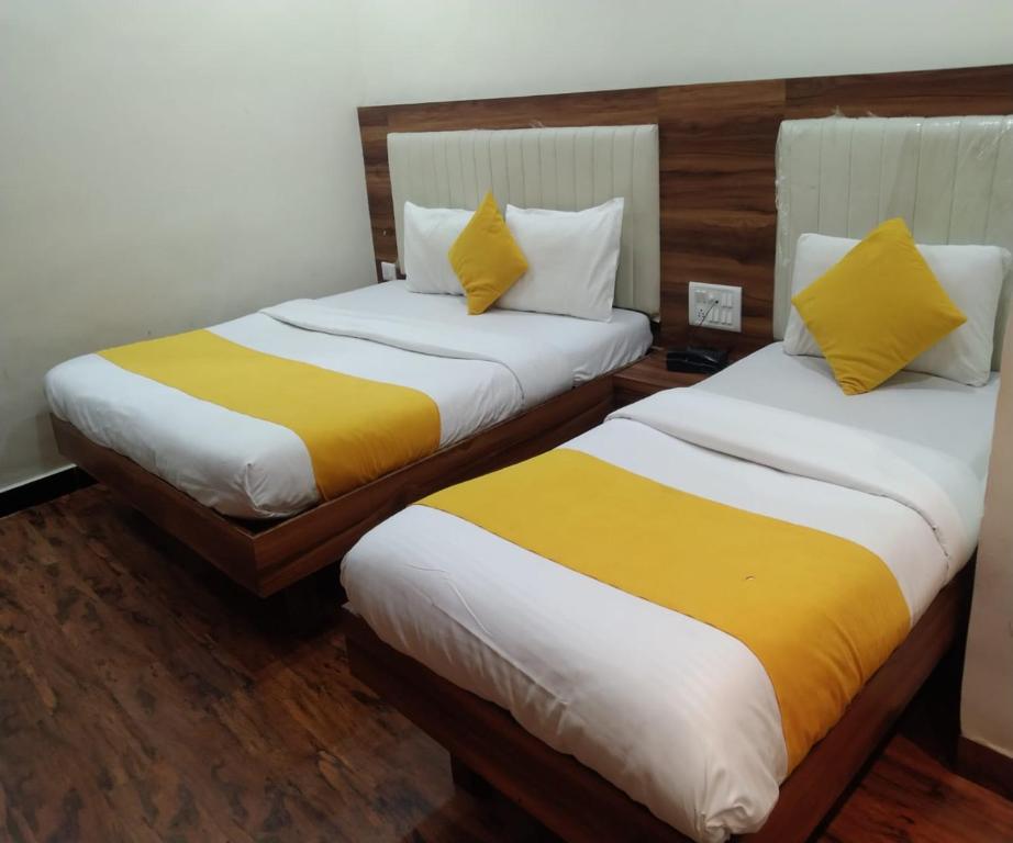 two beds with yellow and white sheets in a room at HOTEL AIR VIEW Near Airport in Mumbai
