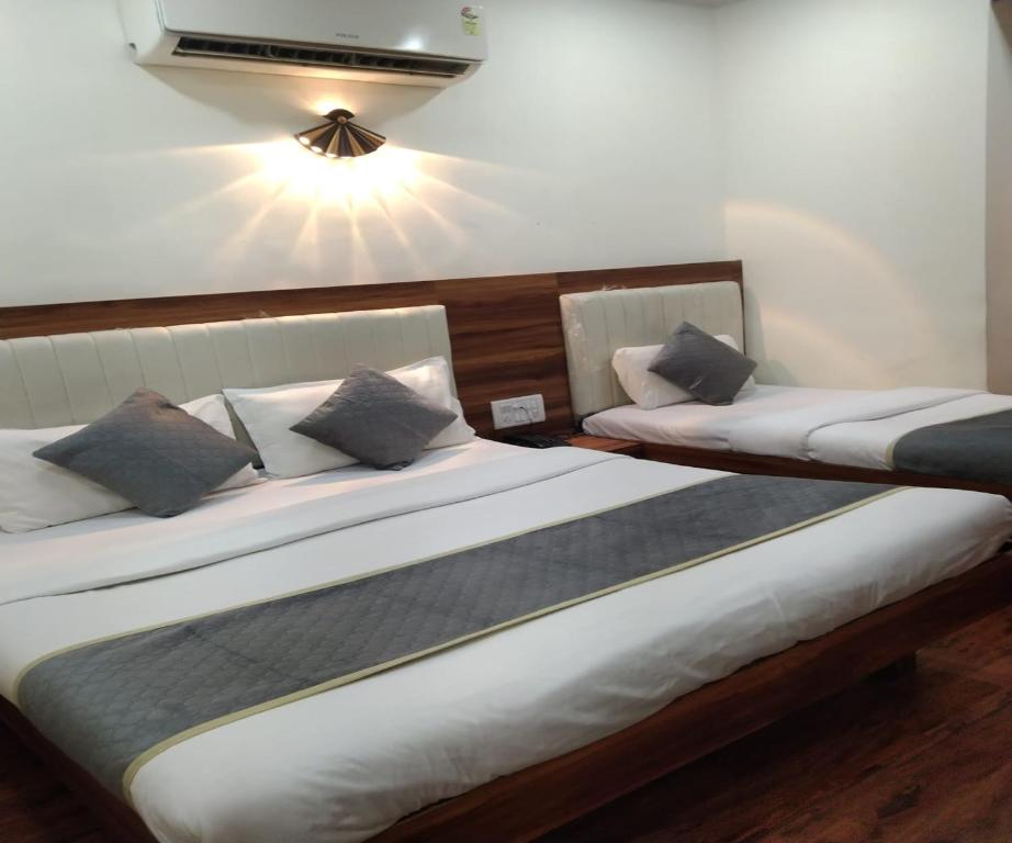 two twin beds in a room with a light on the wall at HOTEL AIR VIEW Near Airport in Mumbai