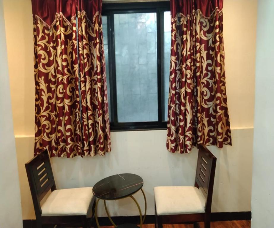 two chairs and a table in front of a window at HOTEL AIR VIEW Near Airport in Mumbai