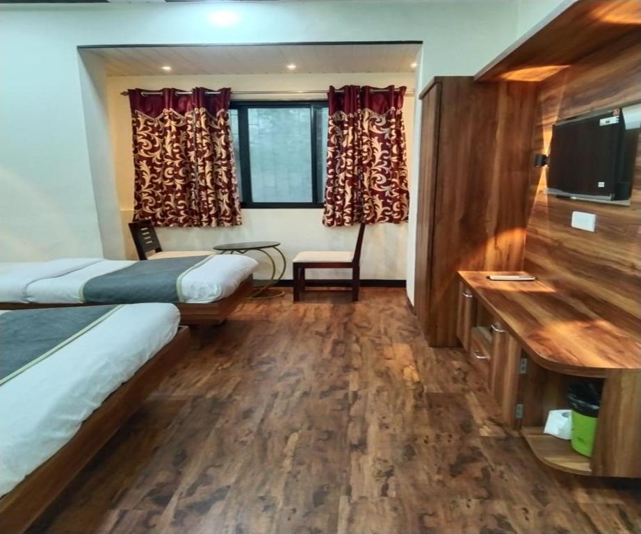 a hotel room with two beds and a desk at HOTEL AIR VIEW Near Airport in Mumbai