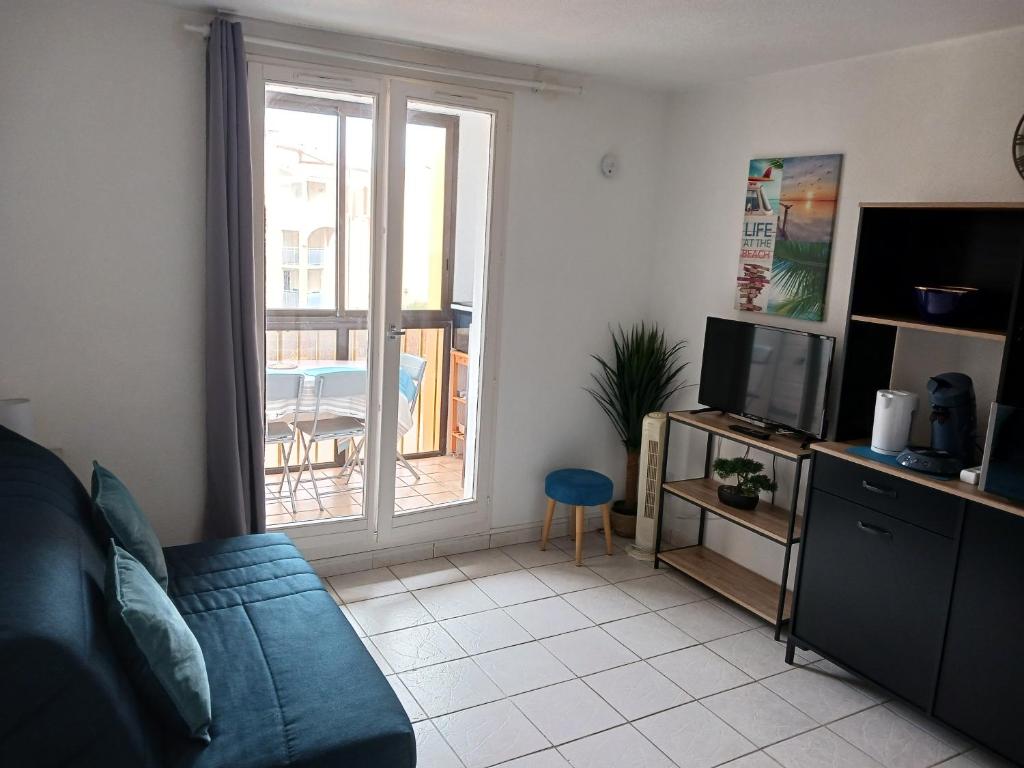 un salon avec un canapé bleu et une télévision dans l'établissement Appartement vue mer latéral, accès direct plage avec parking privé, au Barcarès