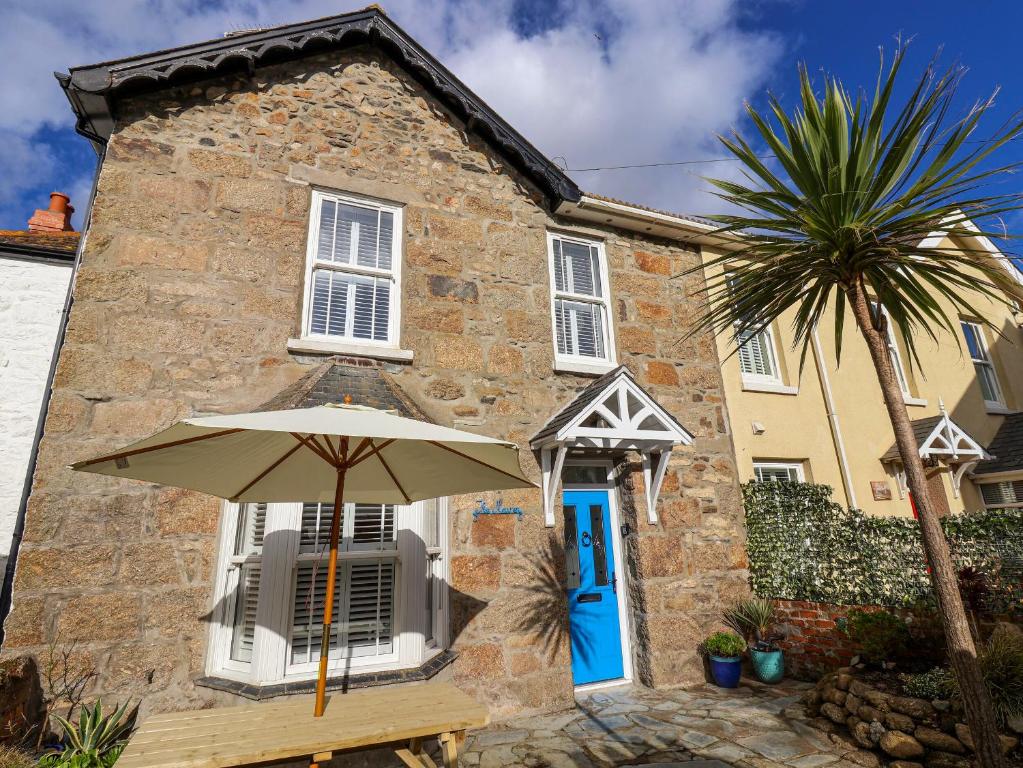 an umbrella in front of a house with a palm tree at The Haven in Marazion