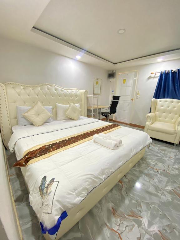 a bedroom with a large white bed and a chair at SUKANO Apartment VIP in Ban Khlong Chao