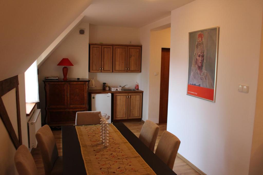 a dining room with a table and a kitchen at Apartament Stara Kamienica in Kętrzyn