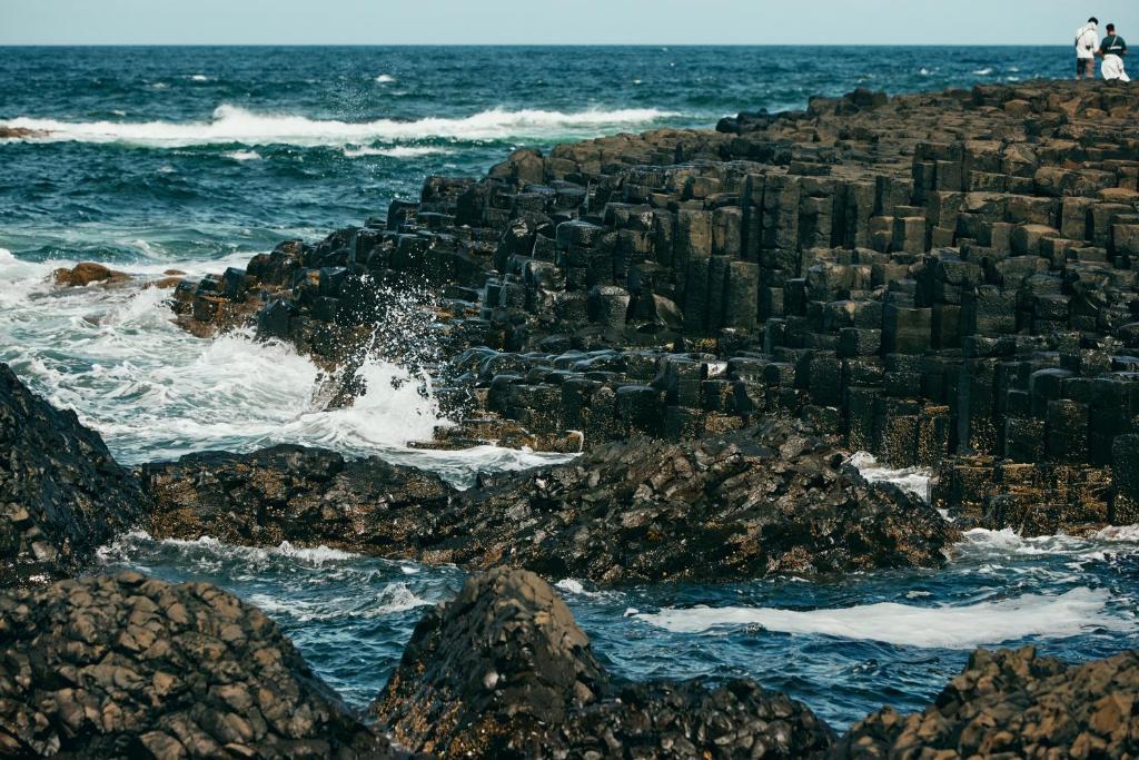 a group of people standing on the rocks near the ocean at Portrush Adelphi in Portrush