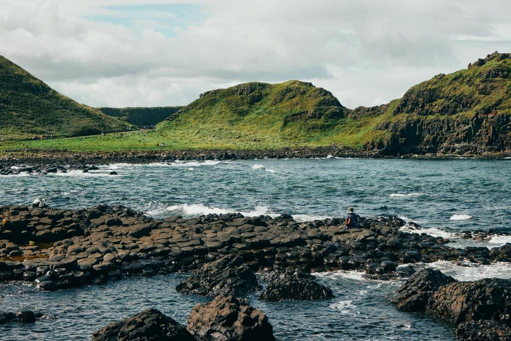 a person sitting on the rocks near the water at Portrush Adelphi in Portrush
