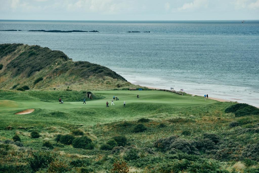 a group of people playing on a golf course next to the ocean at Portrush Adelphi in Portrush