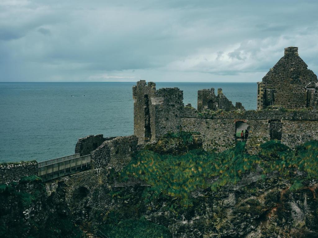 an old castle on a cliff next to the ocean at Portrush Adelphi in Portrush