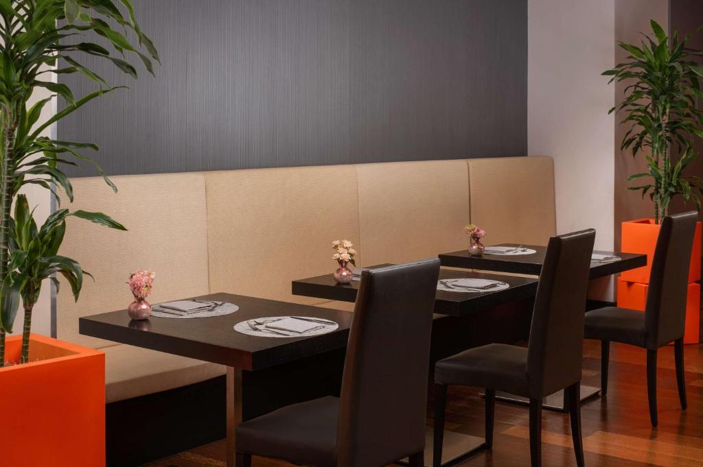 a dining room with two tables and chairs and plants at NH Trieste in Trieste