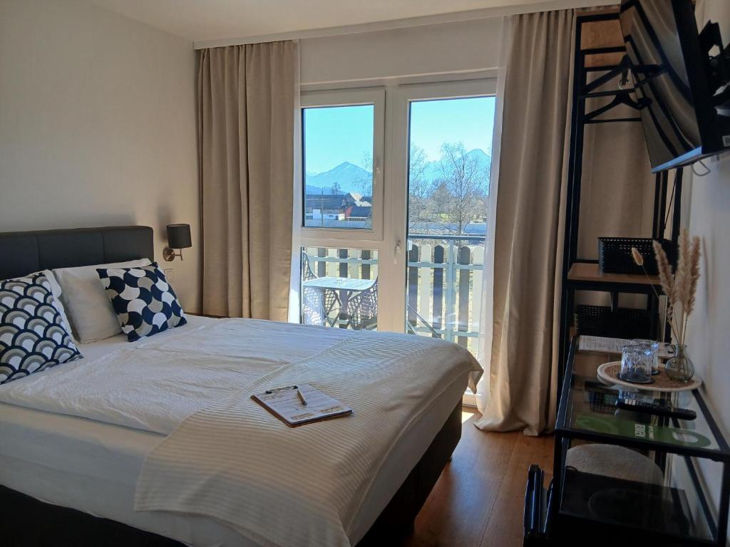 a bedroom with a bed with a view of a balcony at Hotel Fuchs & Hase SELF CHECK IN in Rosegg