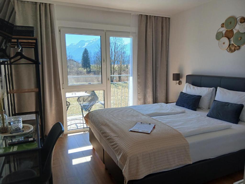 a bedroom with a bed and a large window at Hotel Fuchs & Hase SELF CHECK IN in Rosegg