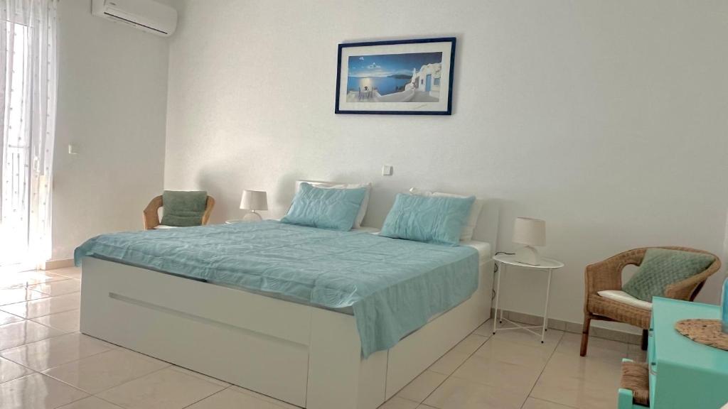 a bedroom with a bed with blue sheets and two chairs at Afandou Blue Apartment in Afantou