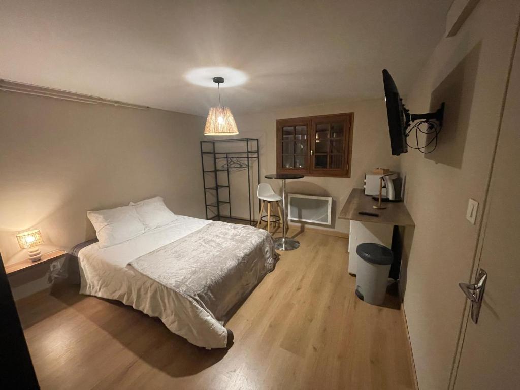une chambre avec un lit, un bureau et une télévision dans l'établissement Chez Simon, à Ussel