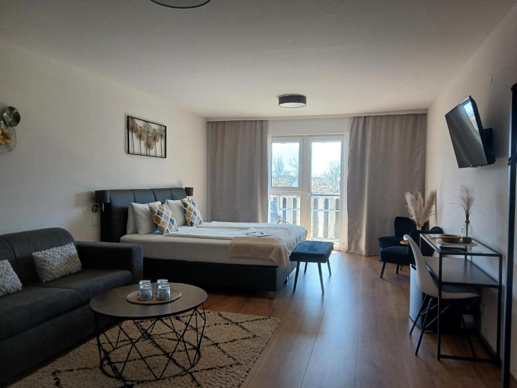 a living room with a bed and a couch at Hotel Fuchs & Hase SELF CHECK IN in Rosegg