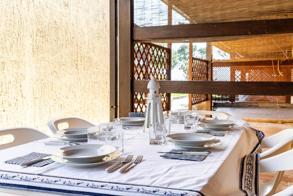 a table with white plates and silverware on it at GuestHost Dreamy Stintino Seafront, AC and Parking in Stintino