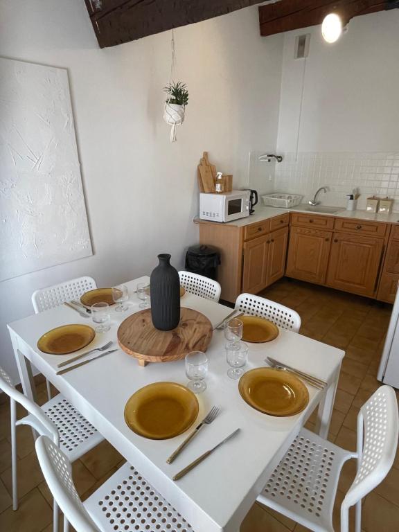 une table blanche avec des assiettes et un vase sur elle dans l'établissement Escapade confort Toulon, à Toulon