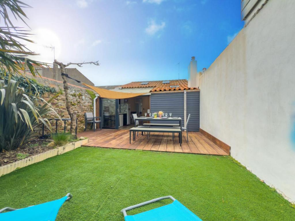 une petite arrière-cour avec une table et une pelouse dans l'établissement Agreable maison de vacances - quartier arago - 6 personnes, à Les Sables-dʼOlonne